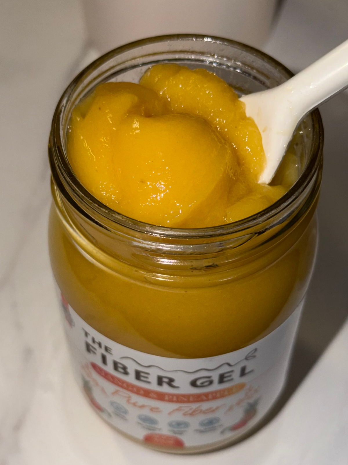 Jar of fiber gel with a spoonful being taken out, on a white background